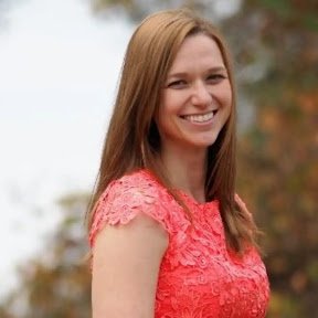 Outdoor photo of a smiling white woman with light brown hair and blue eyes