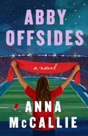 Cover for Abby Offsides, showing a woman in a red shirt holding up a red scarf as she looks out over a packed football stadium on a starry night. Down on the pitch, a solitary man in a red uniform kicks a ball. The book title and author's name, Anna McCallie, are written in bold, blocky letters.