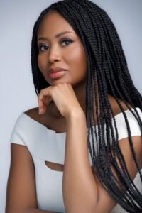 Author Delali Adjoa in a white shirt, turned slightly away from the camera with her hand resting beneath her chin.
