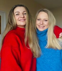 Photo of Katie Ellis-Brown in a red jumper and Becky Hunter in a blue jumper, the two authors of Blood Bound who write under the pen name Ellis Hunter.