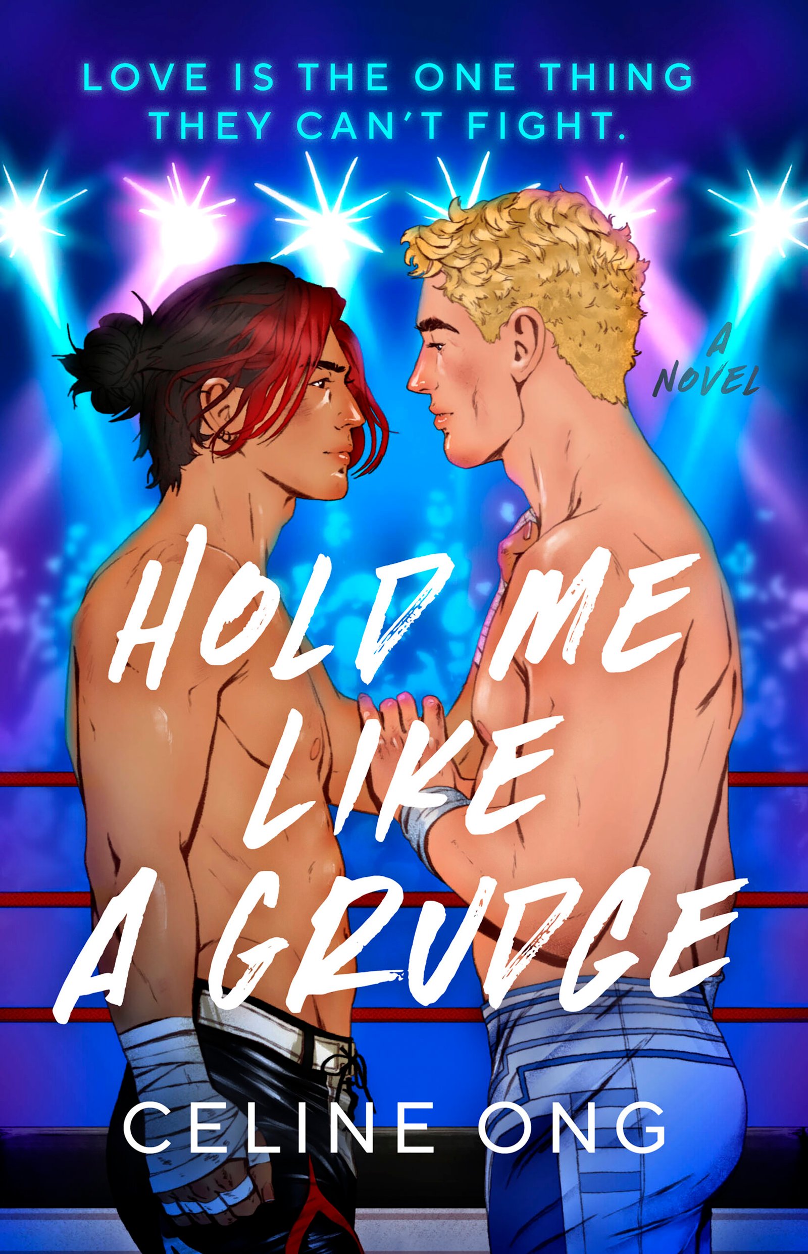The cover art of HOLD ME LIKE A GRUDGE, a novel by Celine Ong, where two male wrestlers (to the left is an Asian man in his 20s with black hair tied up in a man bun and a red fringe cascading down his face, dressed in a pair of black wrestling tights designed to look like flames; to the right is a white man with short blond hair with slight curls at the top, dressed in white tights and blue lines coming up the side) square up in the middle of a ring. They stare at each other with a mix of fierceness and affection, and have an arm on each other. They are illuminated by pinkish, purplish, and blueish stage lights above. In the background, a faceless crowd watches them.