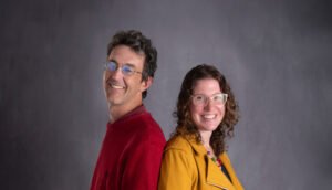 Nate Pieplow and Kate Lumsden stand back to back smiling.