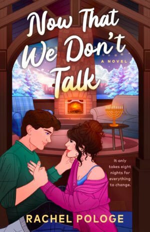 Cover for Now That We Don't Talk, featuring a couple sitting on the floor of a cozy ski lodge, in an embrace, as it snows outside. There is a menorah on a table, and a fireplace lighting up the room.