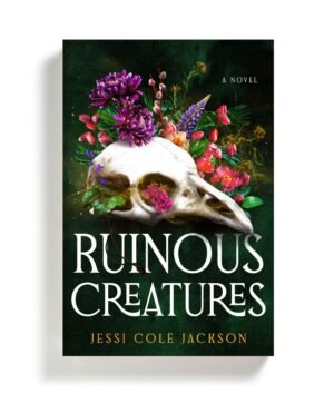 Book cover of RUINOUS CREATURES by Jessi Cole Jackson. A dark background with a phoenix skull and flowers behind it.
