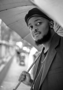 Steven Underwood, an African-American Black man in a beret holding an umbrella. The photo is in black and white.