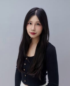 Vivian Jia Lac, an Asian woman with long dark hair, wearing a black top, looking at viewer and smiling.