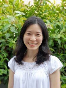 Headshot of Ying Ping Low against a backdrop of greenery.